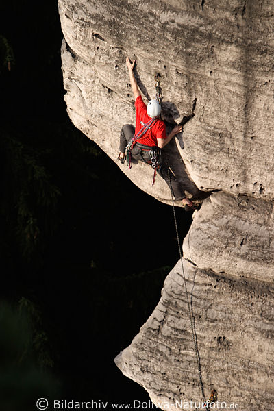 Kletterer Alpinist am Felsvorsprung dunkler Abgrund Kletterwand mit Hnden und Fssen angeklebt