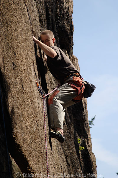 Kletterer Foto Alpinist spannende Momente an steilen Felswand senkrecht hochklettern Sportfoto
