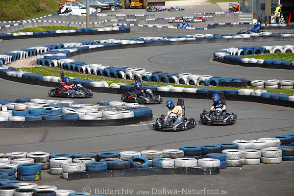 Karting Rennfahrer in Kurve Asphaltbelag Kartbahn Schleifen aus Reifen beim Autorennen