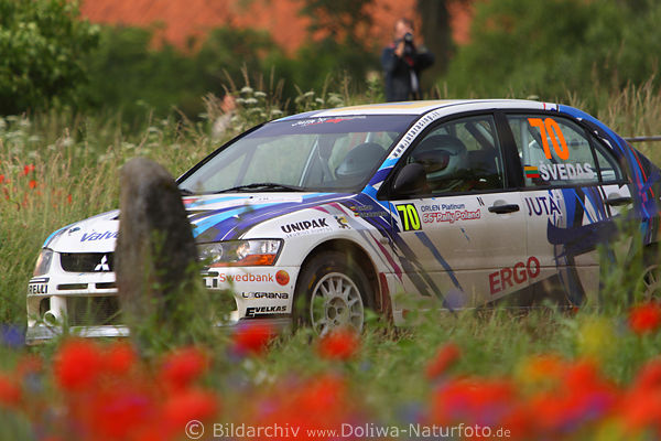 Autorally-Polen Mitsubishi Rennwagen in Mohnbltenfeld verwischten Rotblumen