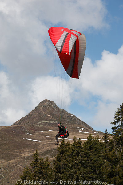 Paragleiter Pilot unter Rotschirm Flugfoto mit Bergsicht auf Gipfel Knoten
