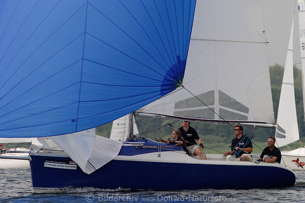 Segler Mannschaft in Boot unter blauer Großsegel bei Regatten auf See hautnah erleben