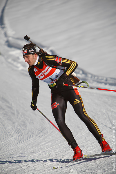 Alexander Wolf Deutschland Biathlet auf weisser Schneeloipe mit Kleinkalibergewehr in Fahrt