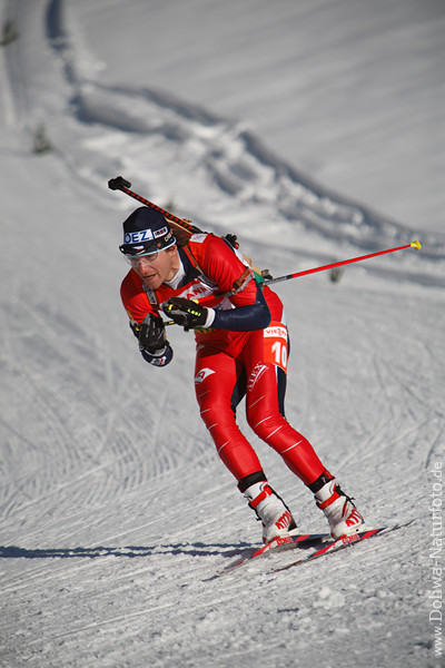 Biathlet Zdenek Vitek Foto auf weissen Schneeloipe mit Kleinkalibergewehr auf Skipiste in Kurve herunterfahren