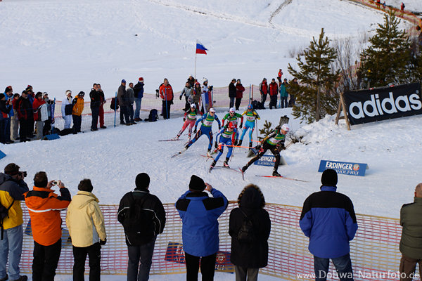 Frauen Biathletinnen Gruppe im Biathlon-Staffelbewerb in Kurve an Zuschauerspalier 