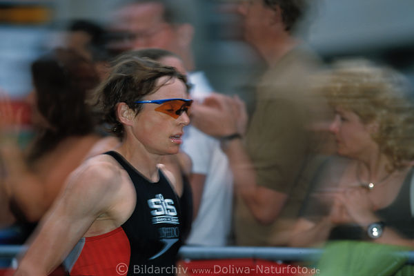 Triathlon Luferin Frau in Bewegungsunschrfe vor Zuschauern-Tribne