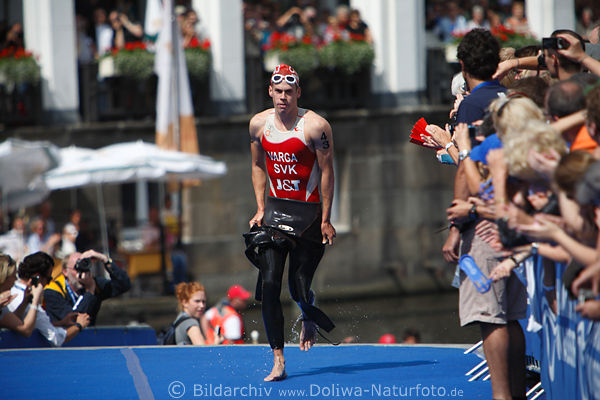 Triathlet Richard Varga Slovakei Spitzenathlet auf Blauteppich im Publikumspalier nach Schwimmen