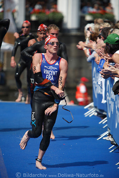 Triathlete Yohann Vincent Lauf im Schwimmanzug ausziehend auf blauen WM-Teppich