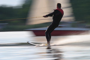 Wasserski Foto Mann Skifahrer Rauschtempo dynamisches Bild auf Wasserwelle gleiten an Leine