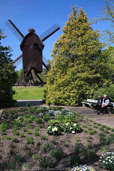 Besucher Paar Senioren Foto auf Gartenbank vor alter Holzmhle Bild an Blumenrabatten