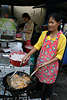 Marktverkäuferin macht Brat-Hähnchenflügel auf Thai-Art in Pfanne auf Markt